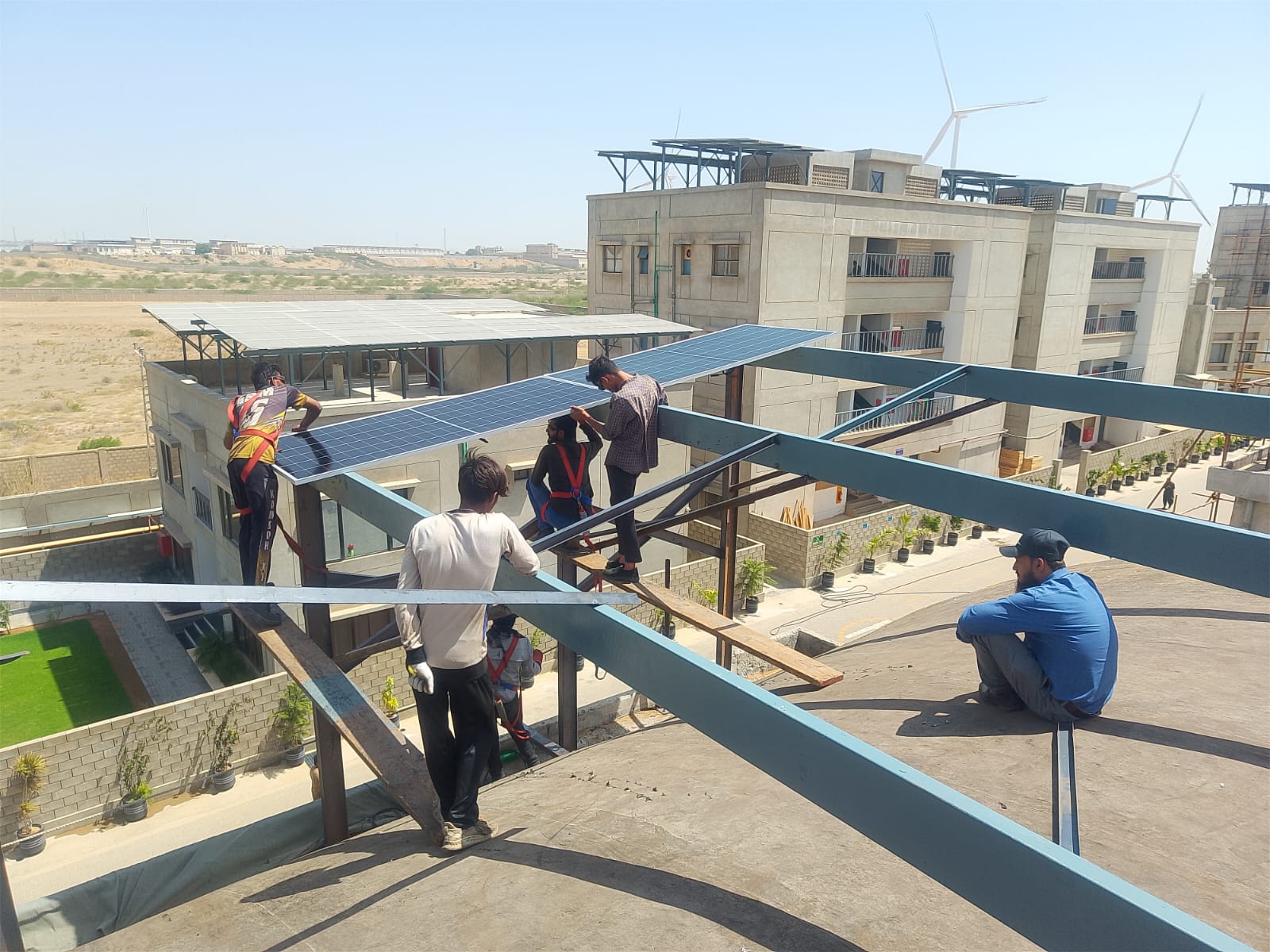 AEIW crew installing an elevated solar panel structure on a Karachi rooftop